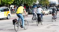 Personer sedda bakifrån som cyklar på stadsgata