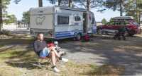 man sitter i campingstol framför Polar husvagn på campingplats