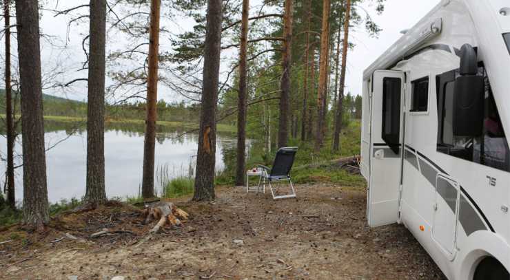 Husbil parkerad intill sjö, med stol utanför