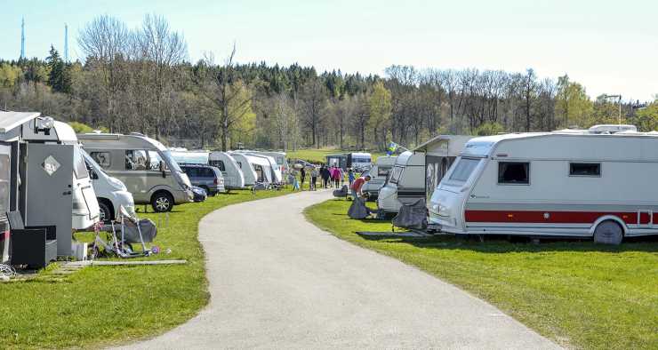 Parkerade husvagnar på camping med människor som tittar i bakgrunden