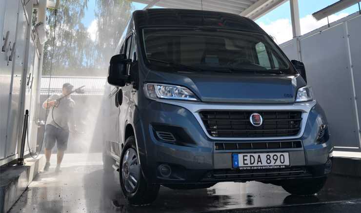 Man i shorts sprutar vatten på husbil byggd på Fiat Ducato