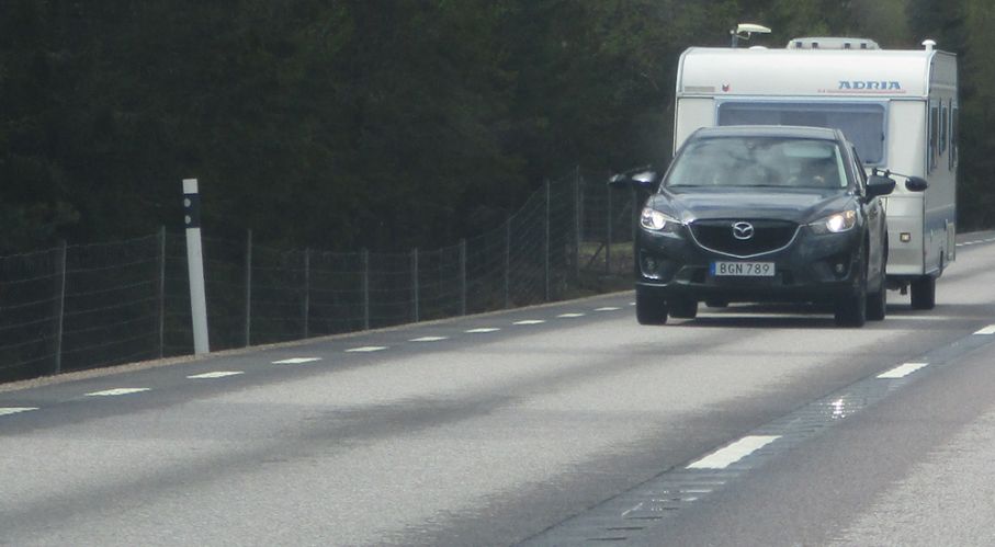 Bil och husvagn på sliten väg