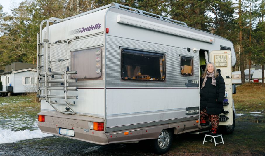 Kerstin carneroth dethleffs Kvinna står på trappsteget till äldre husbil. Snö på marken