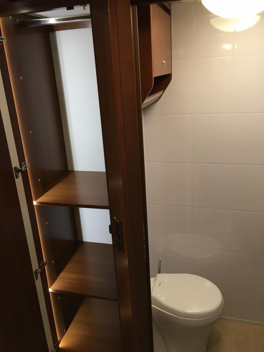 Stor garderob med hyllplan. Toaletten har en egen dörr att stänga om andra vill passera i mittgången eller duscha.