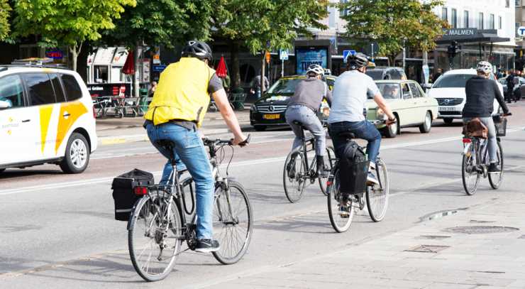Personer sedda bakifrån som cyklar på stadsgata